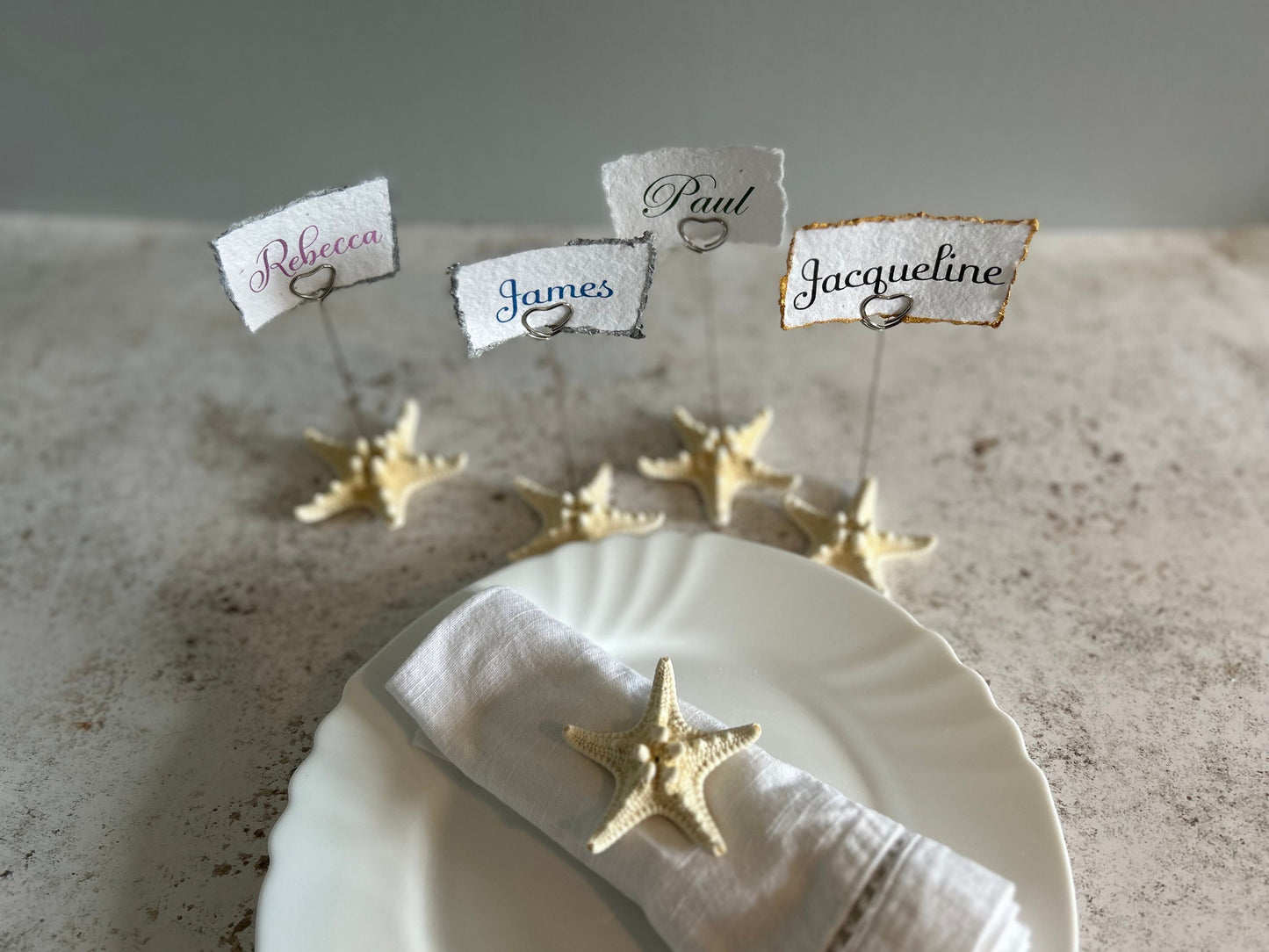The place cards are attached to starfish with gold wire holders with a heart clip to hold your place card.