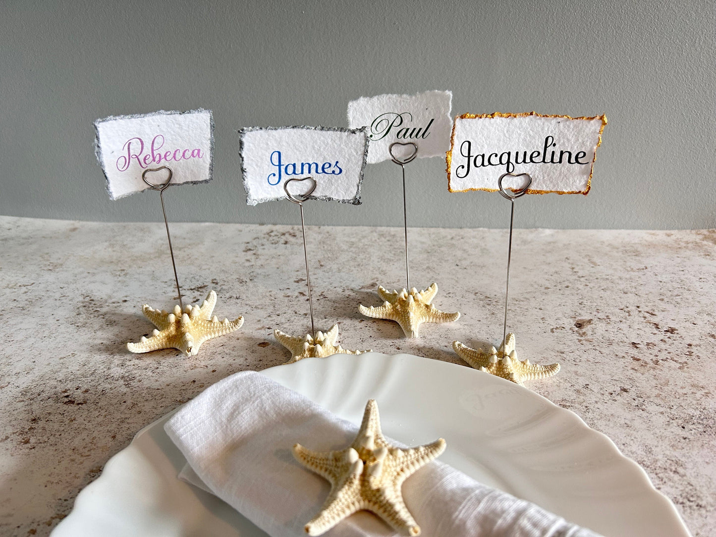 card holders with starfish bases and a silver wire heart shaped clip. The place cards are made of hand torn seeded card.