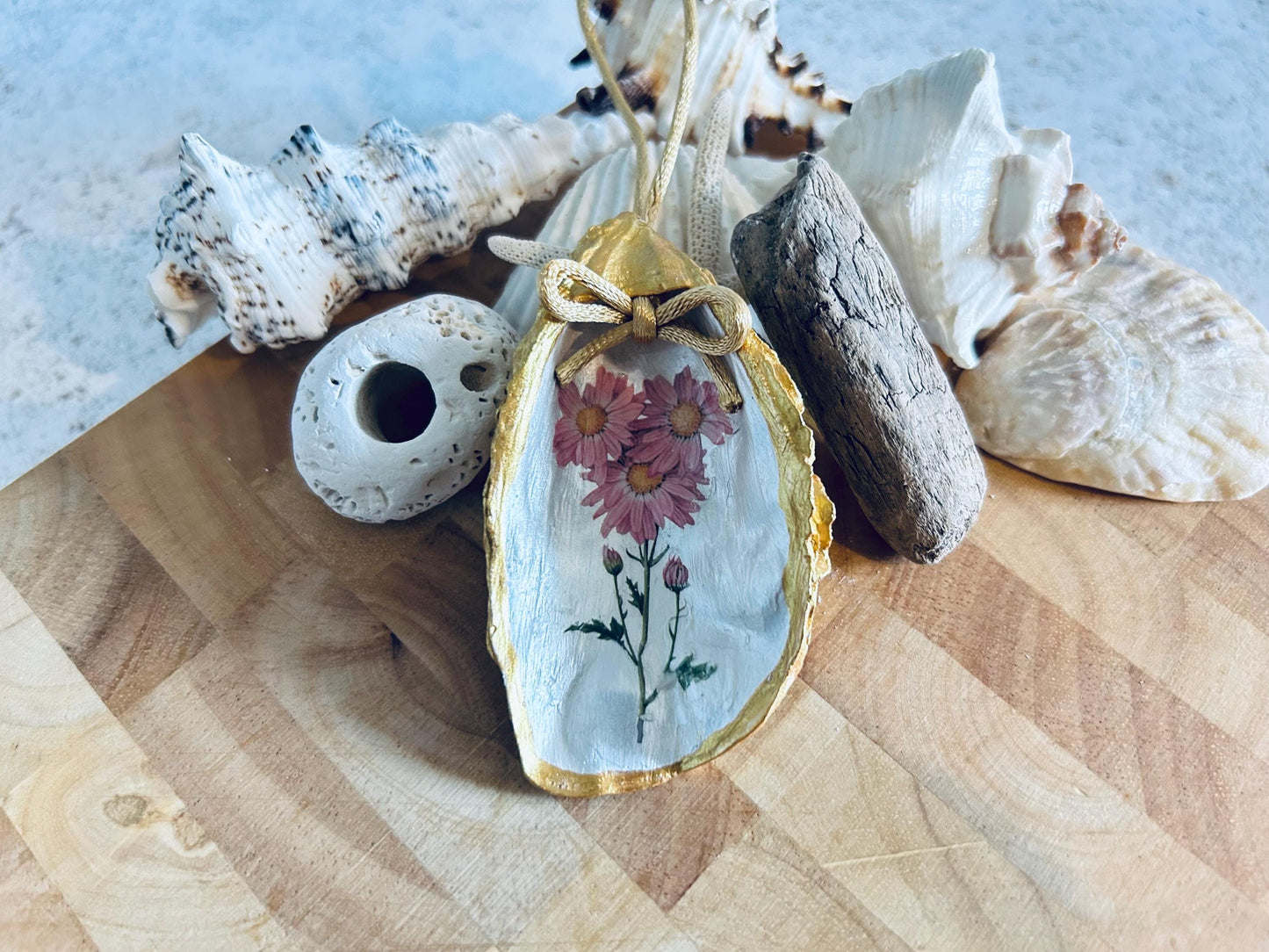 Pastel pink daisy and gold oyster shell decoration.