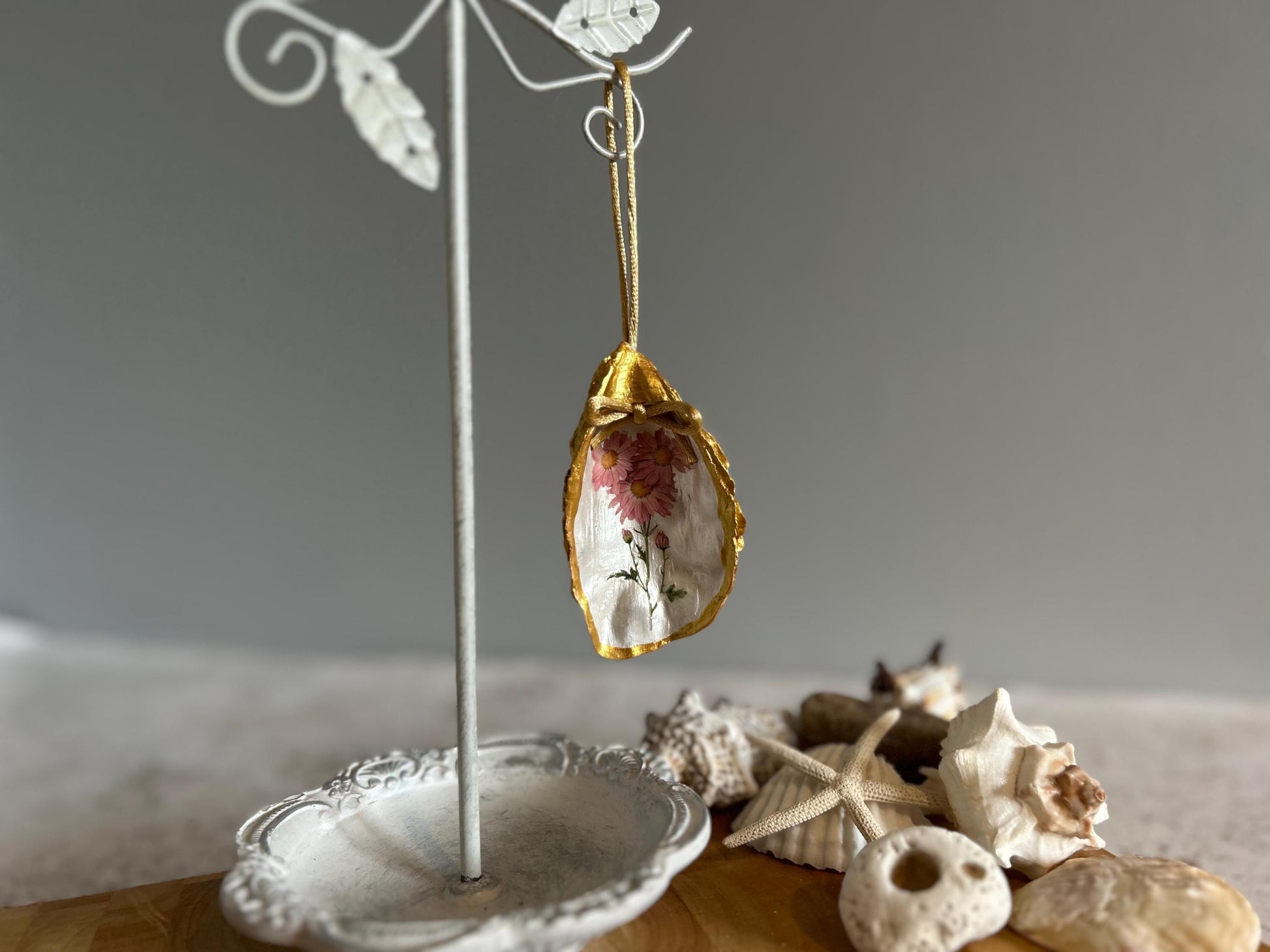 Pastel pink daisy and gold oyster shell decoration.