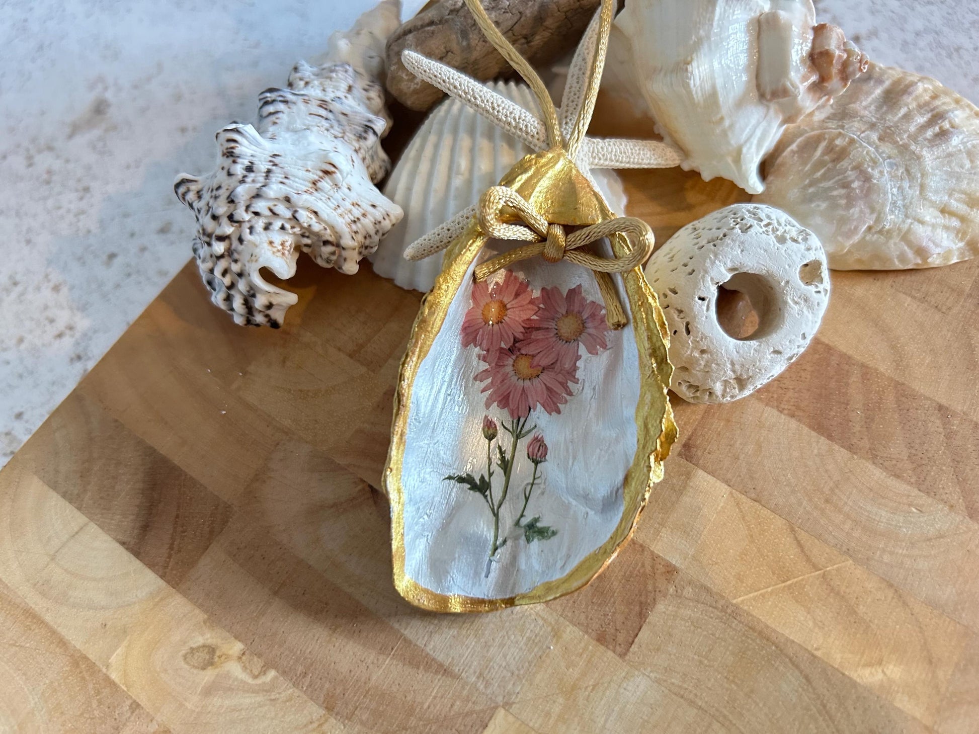 Pastel pink daisy and gold oyster shell decoration.