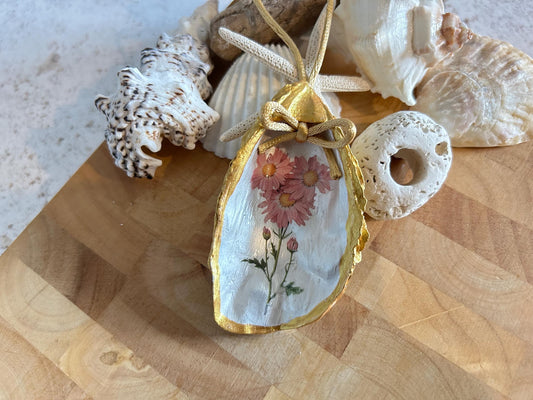 Pastel pink daisy and gold oyster shell decoration.