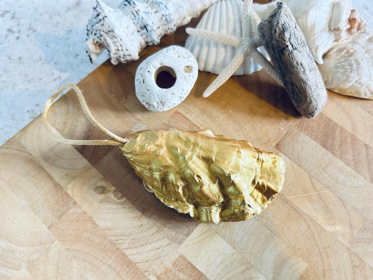 Pastel pink daisy and gold oyster shell decoration.