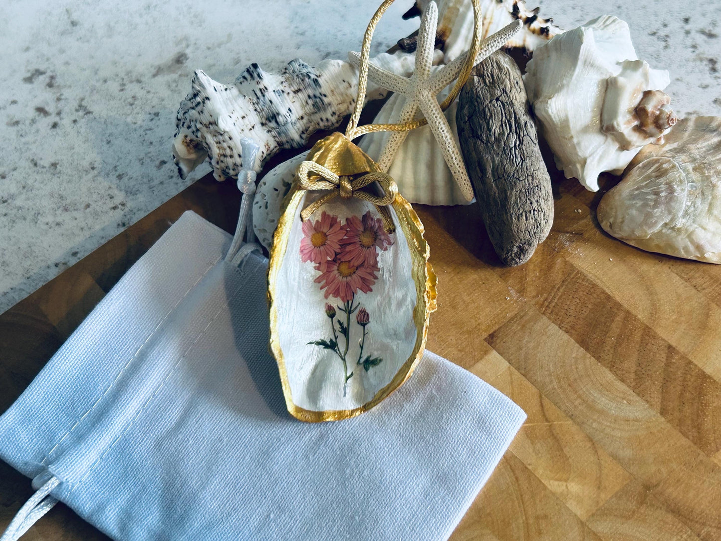 Pastel pink daisy and gold oyster shell decoration.
