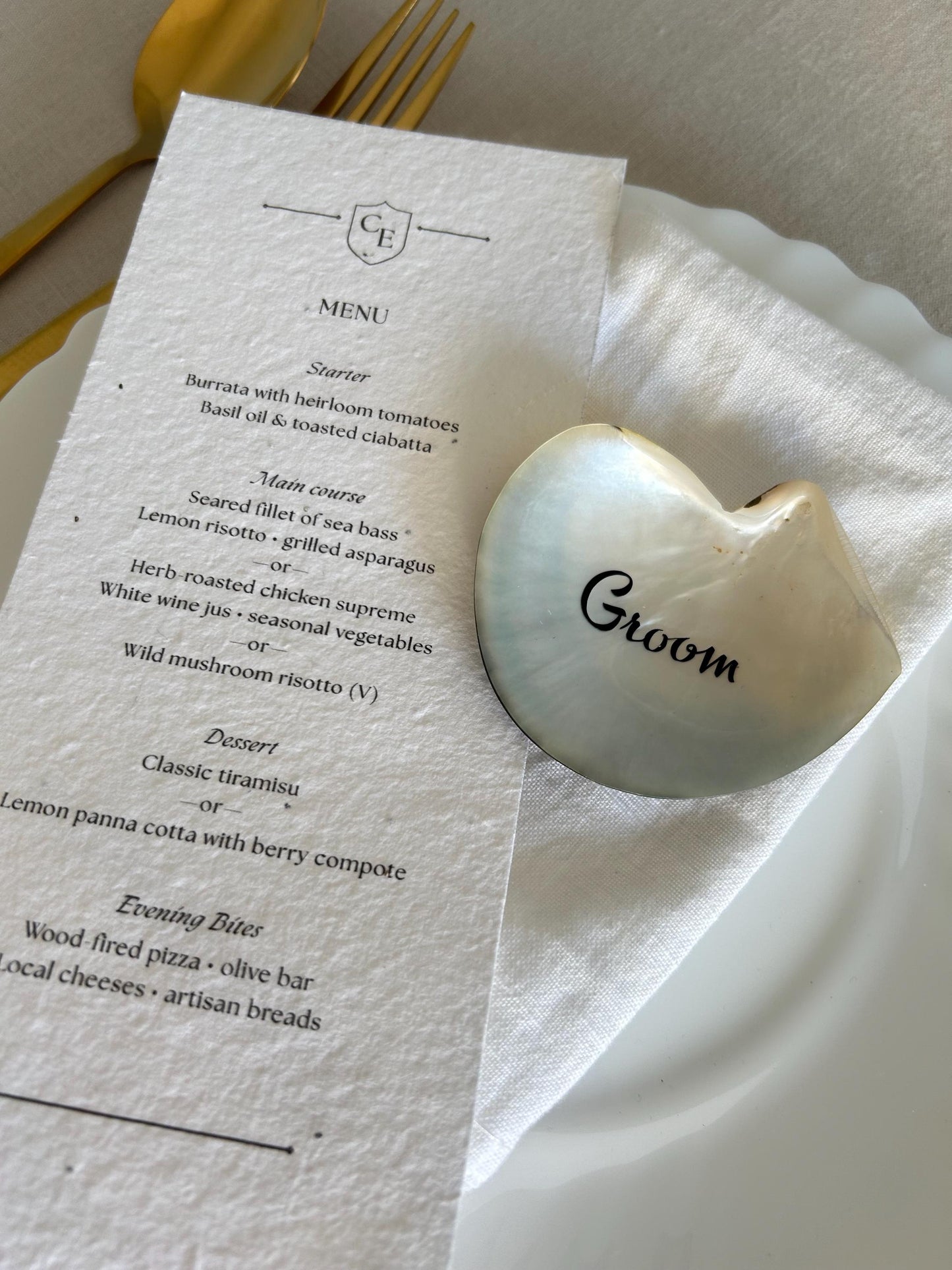A decorative black lip oyster shell with the word "Groom" is placed on a white napkin.