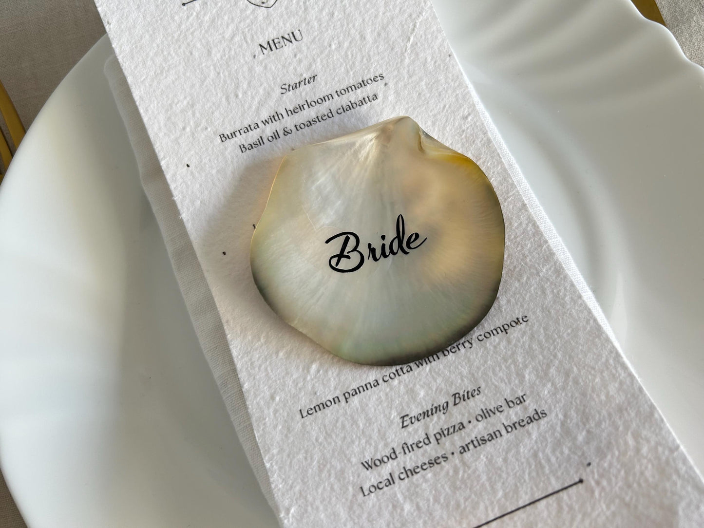 A mother-of-pearl place card shell, personalised with the word "Bride"perfect for any  wedding reception.